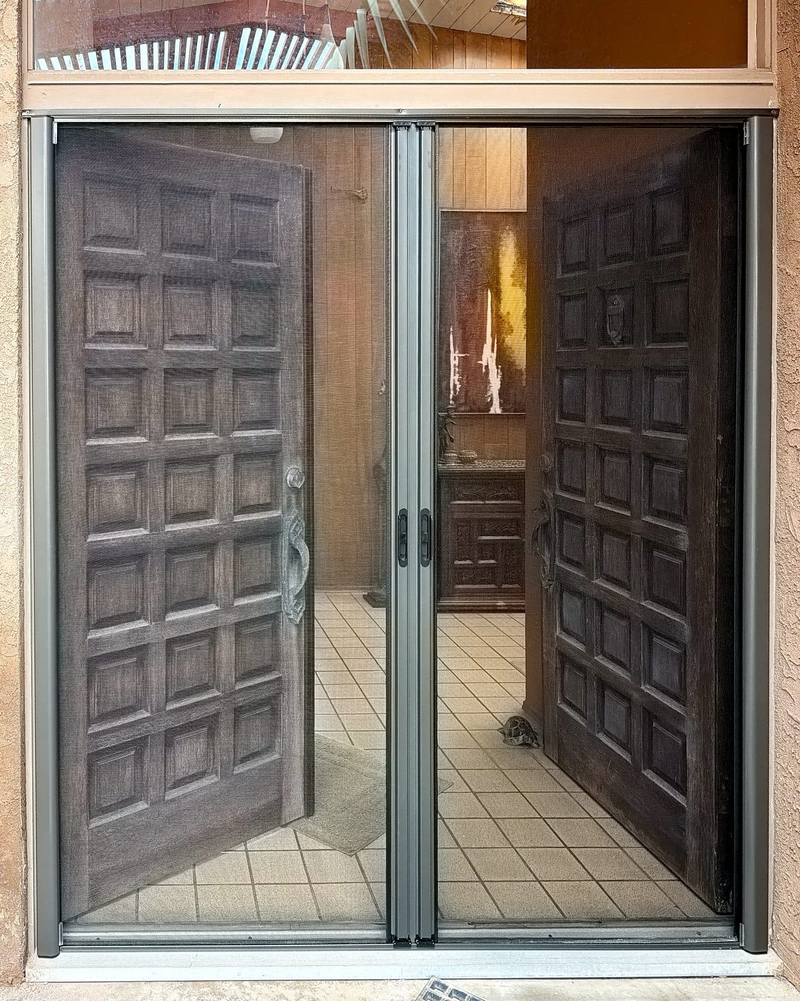 Retractable French screen set closed in front of open carved wooden double doors