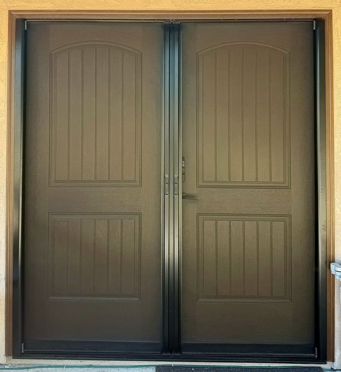 Retractable screens pulled closed across a brown double front door, French set