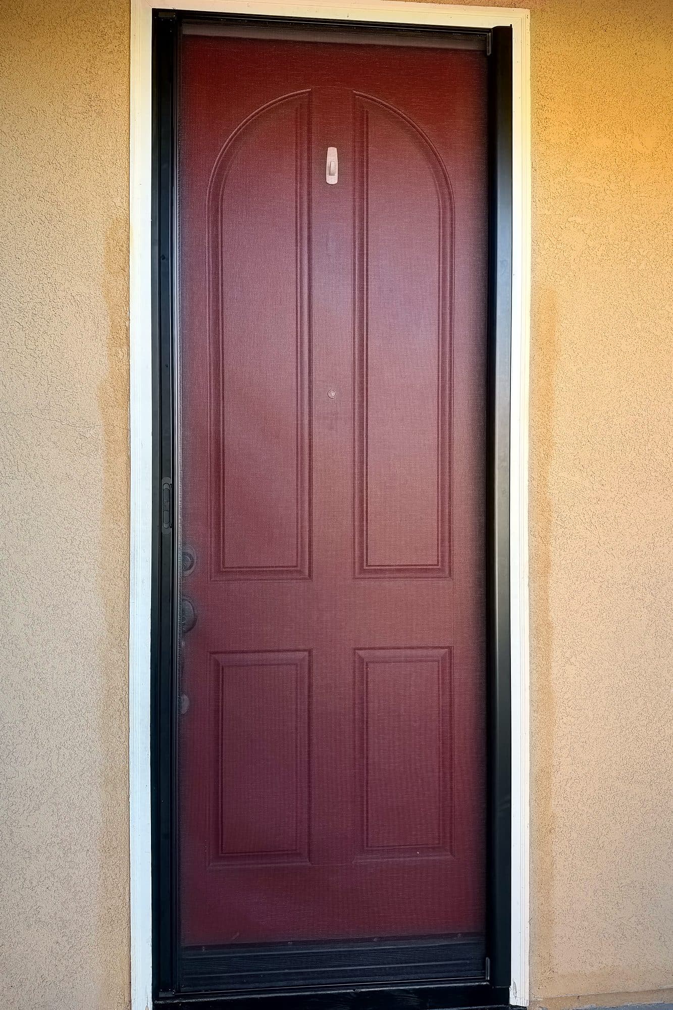 Retractable screen pulled closed over a red single front door