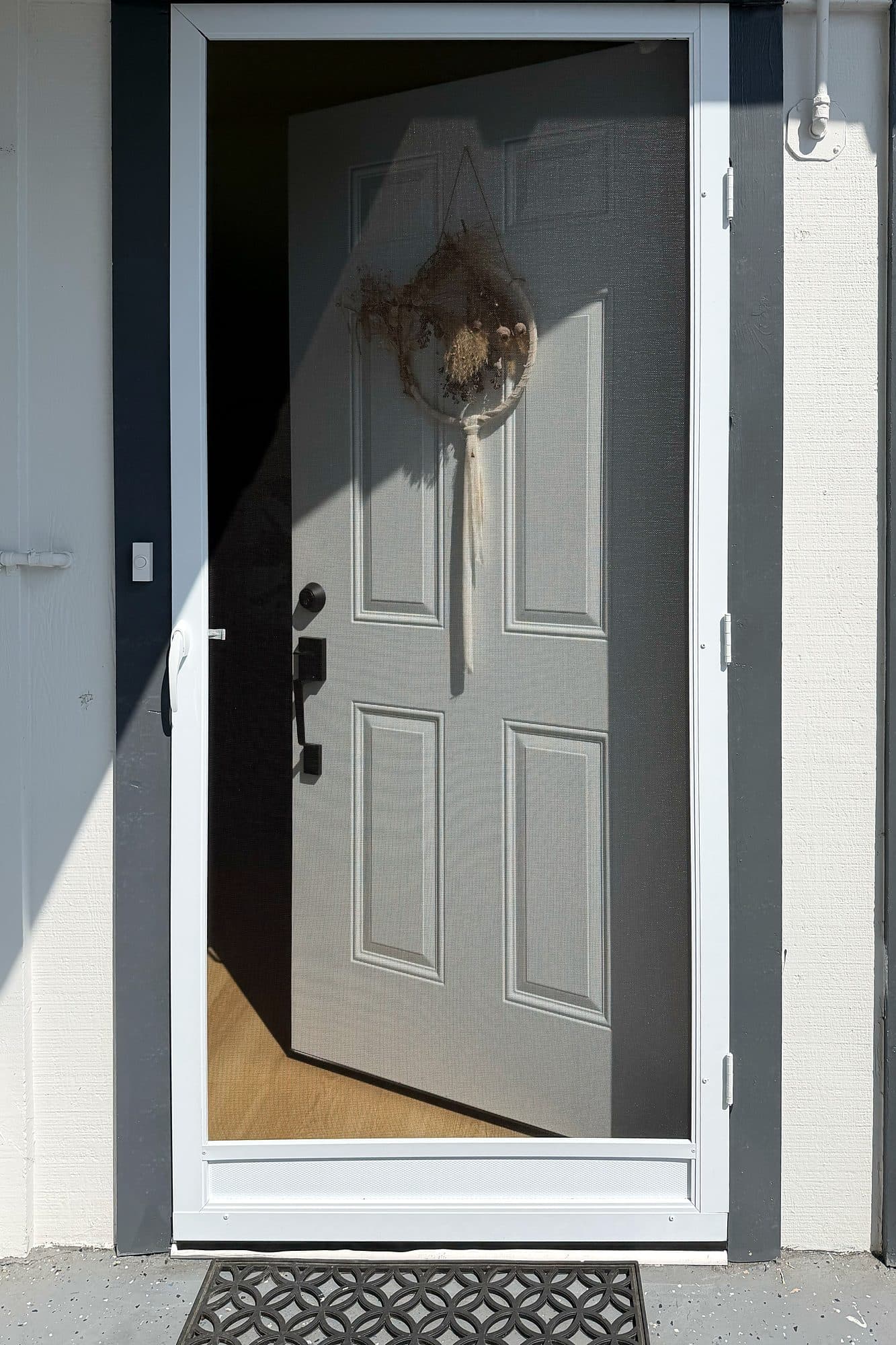 White swinging screen door installed on a gray front entry in San Diego
